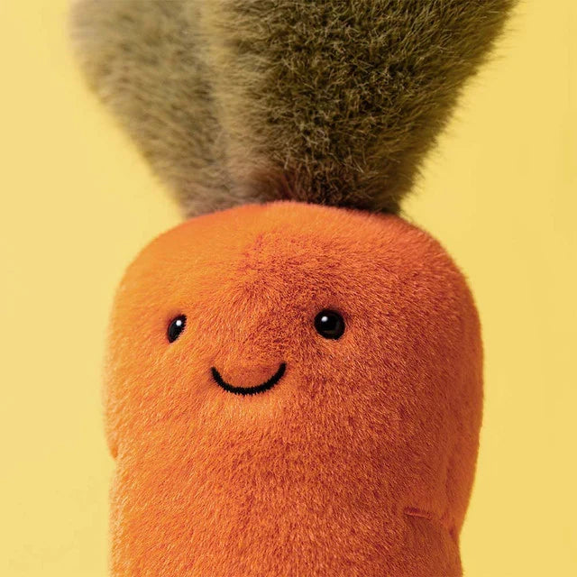 Plush toy carrot with a smiling face on a yellow background