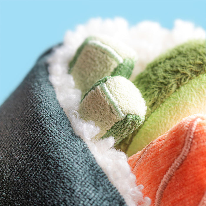 Close-up of a textured fabric resembling the interior of a sushi roll with green, orange, and white patterns against a blue background