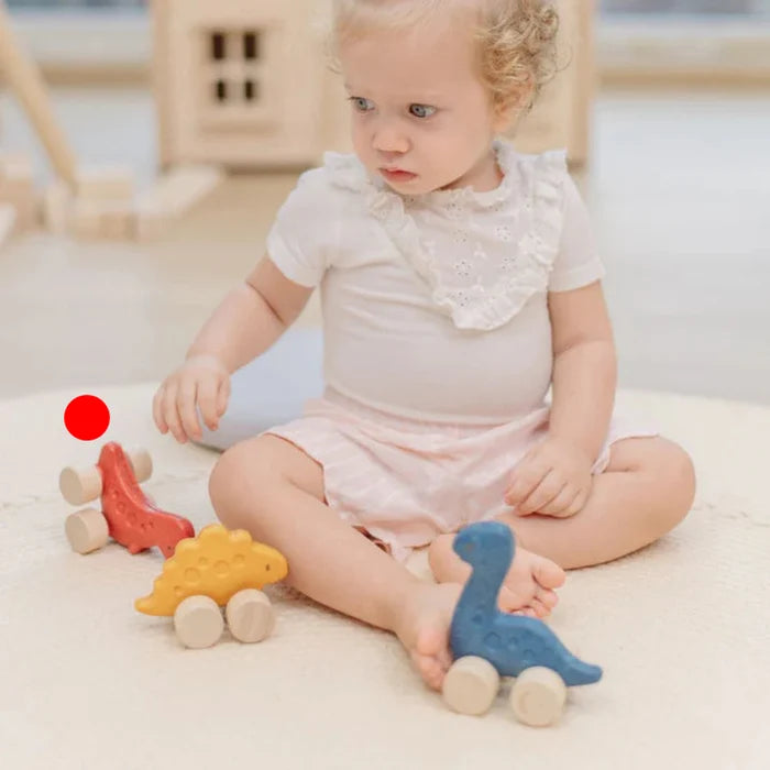 Child playing with wooden toys on a light-colored floor.
