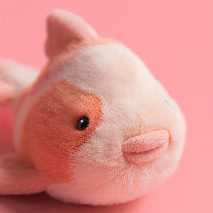 Close-up of a  jellycat fancy carp soft toy with a pink background