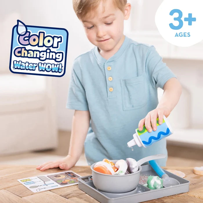 Child playing with a color-changing water toy on a wooden table.
