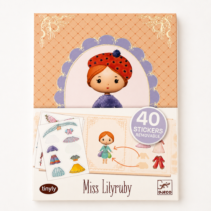 A boxed sticker activity product labeled 'Miss Lilyruby' with '40 stickers removable' shown on the front. The packaging features a pastel illustration of a girl with red hair and a red polka-dot hat on an orange patterned background, with sample sticker sheets and clothing stickers visible below.
