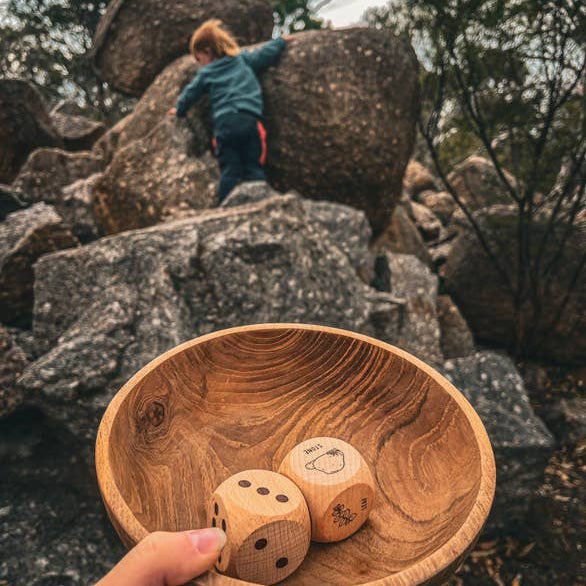 Child climbing a rocky mountain with a wooden bowl containing dice.
