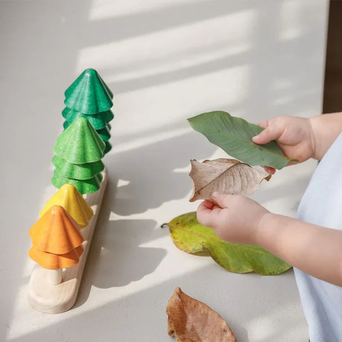 Wooden tree toys with leaves on a light surface